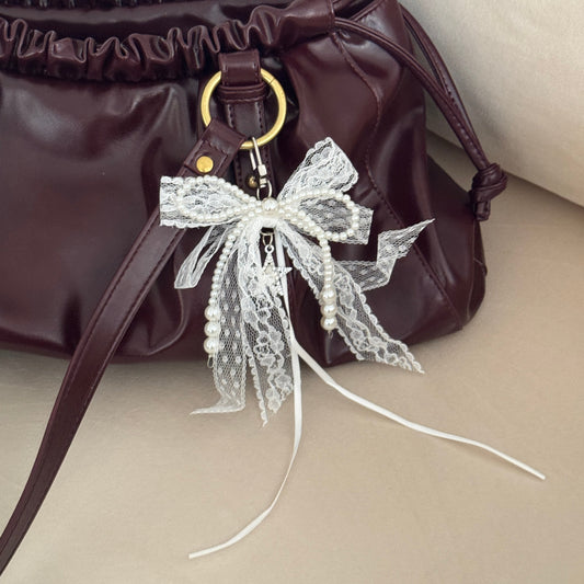 Brown handbag with decorative bow on a beige background
