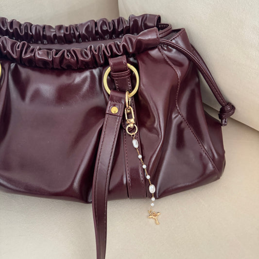 Brown handbag with a gold clasp on a light background