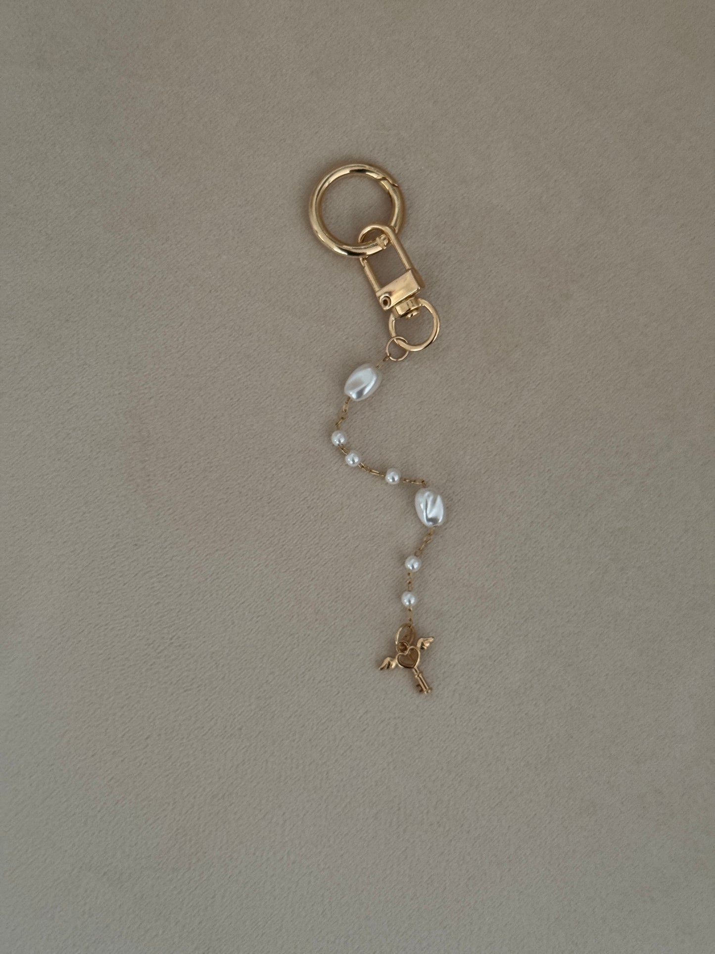 Gold keychain with a chain on a beige background