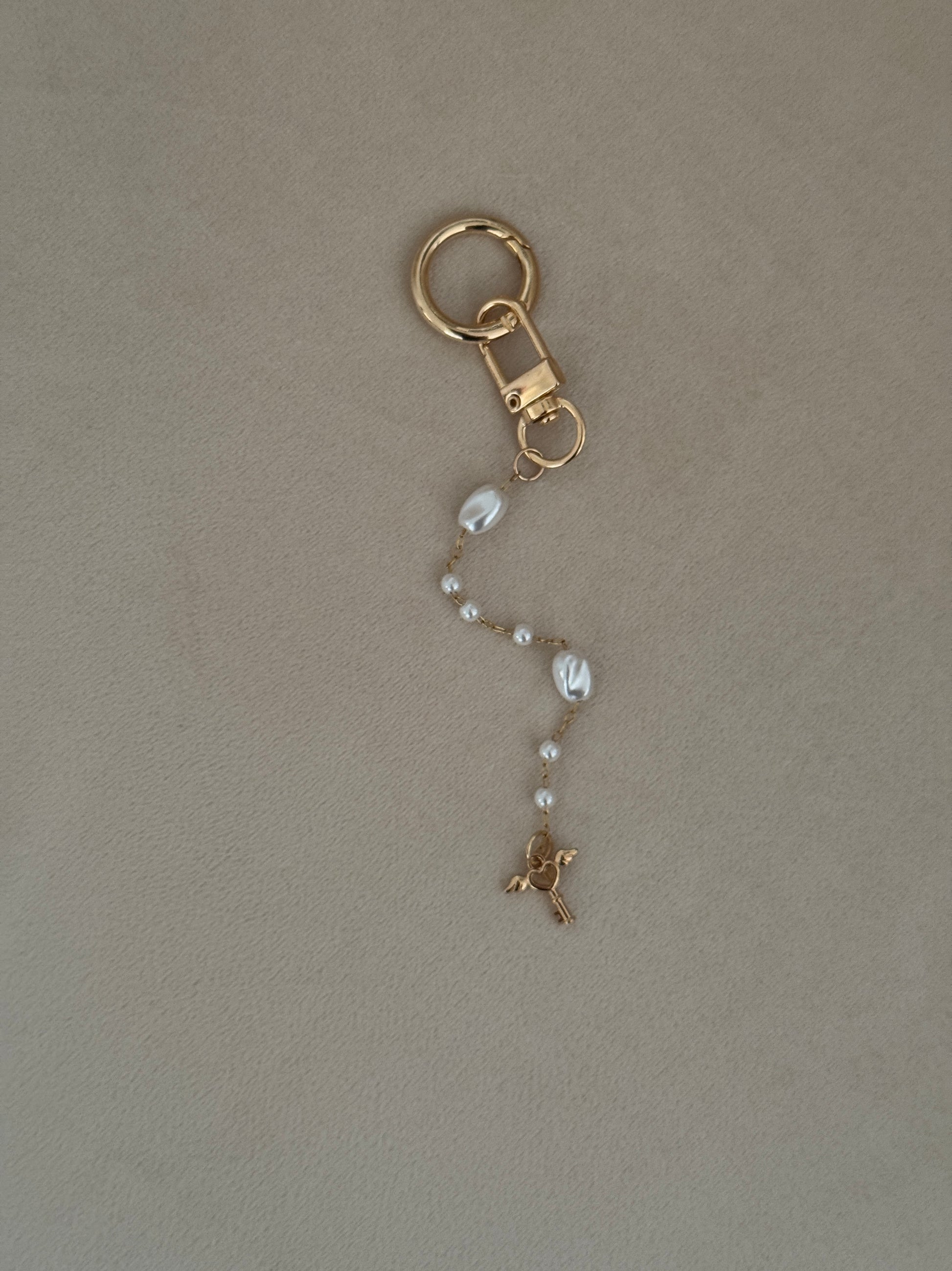 Gold keychain with a chain on a beige background