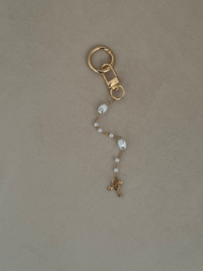 Gold keychain with a chain on a beige background