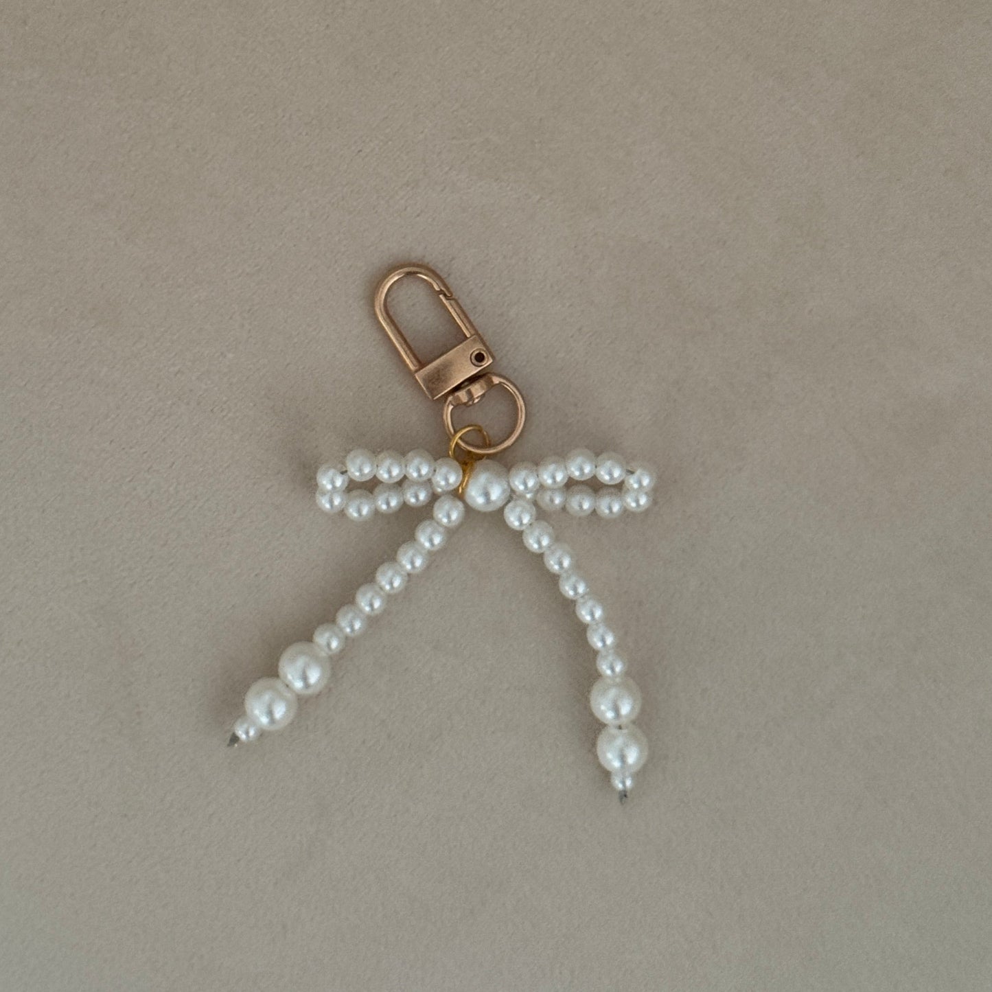 Pearl bow keychain on a beige surface