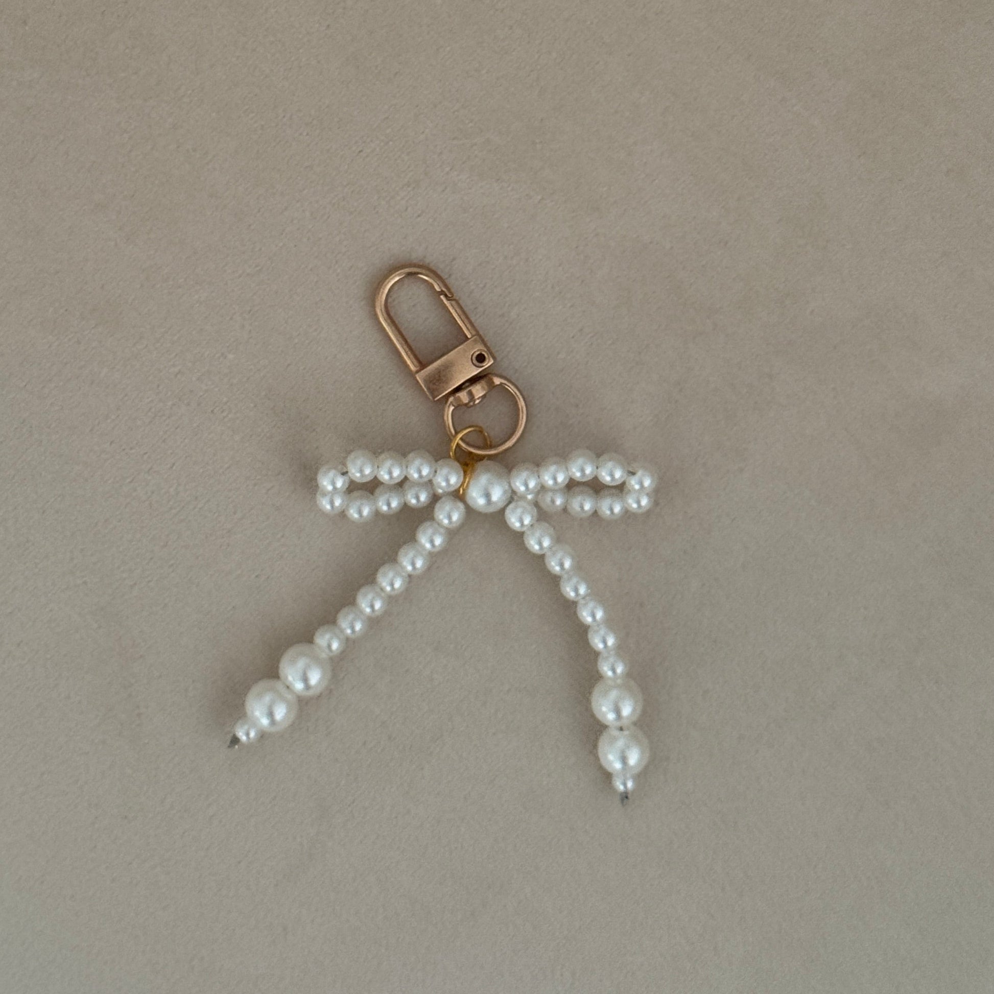 Pearl bow keychain on a beige surface
